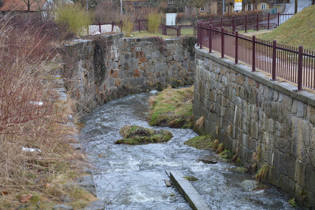 Wasserlauf eines Baches zwischen Dorfmauern