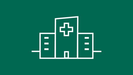 Piktogramm: weiße Linien auf dunkelgrünem Hintergrund zeigen ein großes mehteiliges Gebäude mit medizinischem Kreuz oben in der Mitte